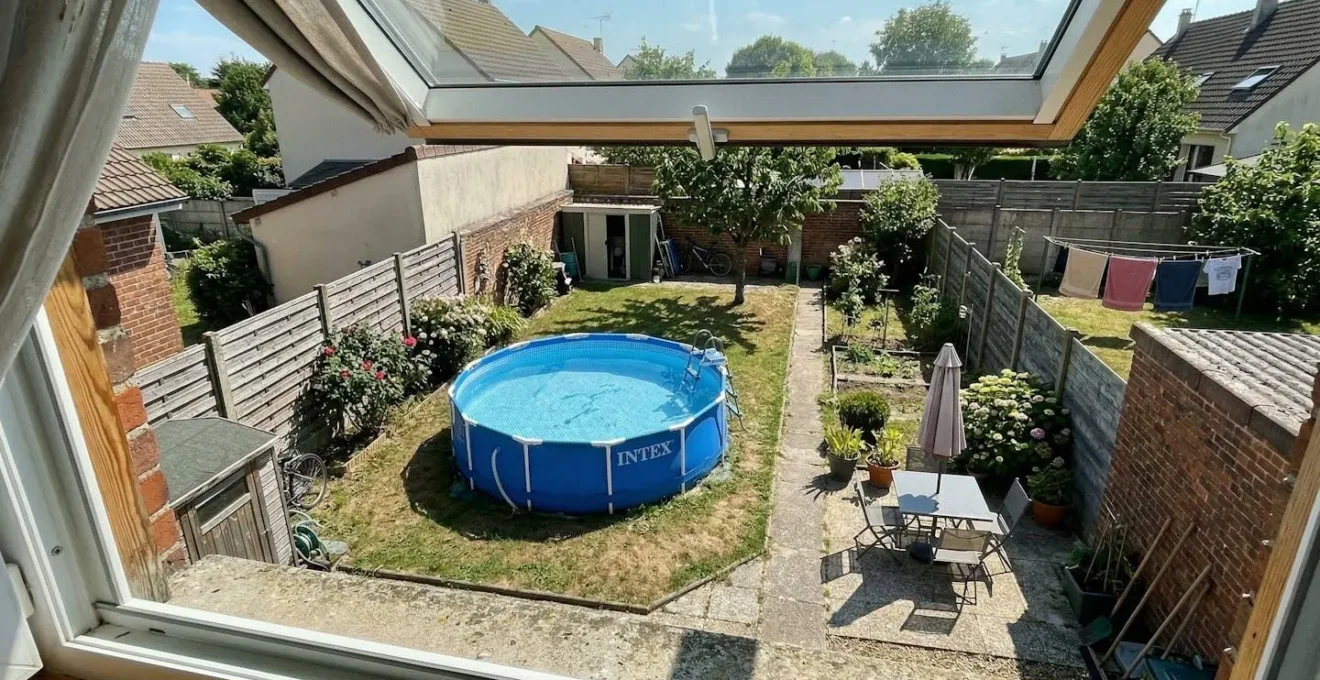 Vue plongeante sur un petit jardin de maison avec une piscine tubulaire ronde installée, montrant clairement les espaces de circulation autour